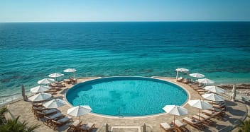 Privates Badebucht eines Erwachsenenhotels mit Sonnenschirmen und türkisfarbenem Meer