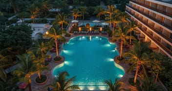 Luxuriöses Adults-Only Resort mit großer Poolanlage und Palmen bei Sonnenuntergang