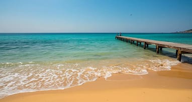 Goldener Sandstrand am Mittelmeer mit Steg und türkisfarbenem Wasser